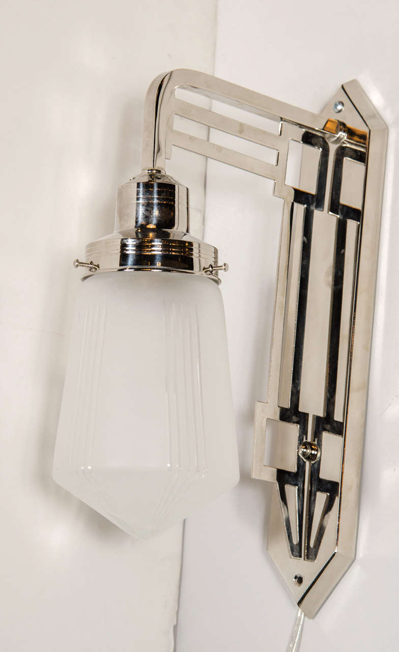 Art Deco Bauhaus style sconce in the manner of Josef Hoffman in polished nickel with a frosted glass globe with etching details. This sconce is in a polished nickel featuring a canopy with a skyscraper styling and an elongated hexagon shape. From