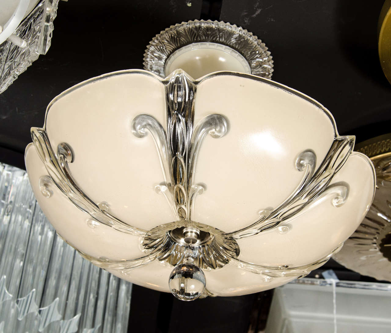 Art Deco molded and relief glass dome chandelier. The glass dome of this chandelier features a stylized fleur-de-lys design that spans out from its center point. It is capped by a glass ball drop in the center. The dome is then suspended by its