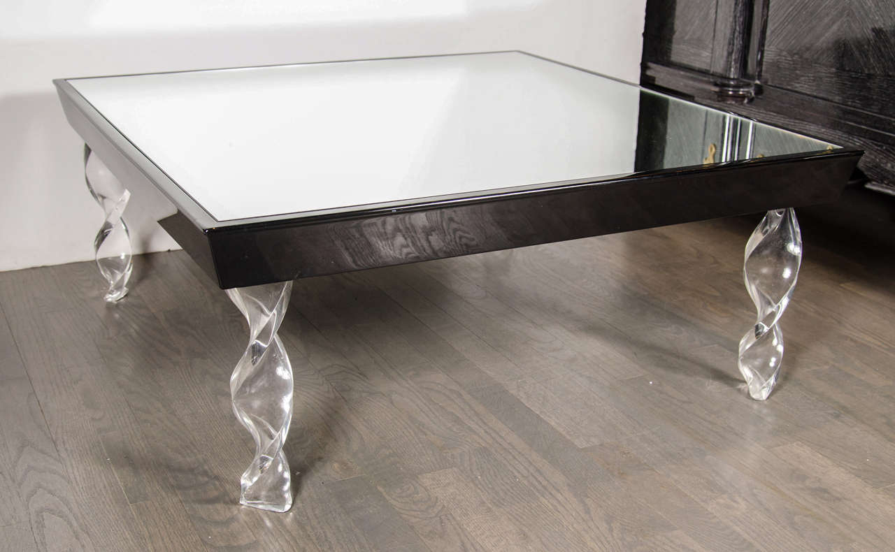 This elegant Art Deco cocktail table by Grosfeld House features twisted ribbons of clear lucite legs supporting a square mirrored table top framed in black lacquer. A matching occasional table is also available. Restored to mint