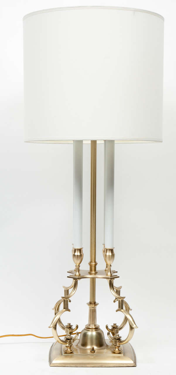 Pair of 1960s glam satin brass candelabra lamps with four white enamel columns and double light source. Lamps have on and off switch at base and have been rewired with gold silk cords. Style of Tommi Parzinger.
