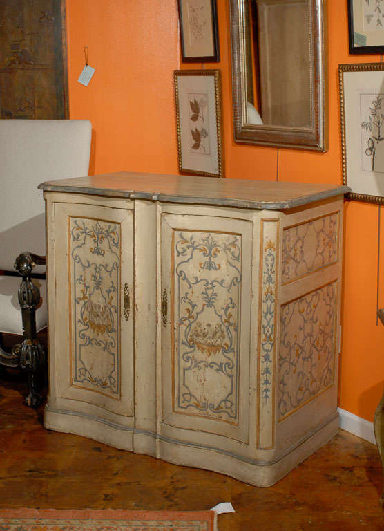 19th century paint decorated French buffet, the shaped rectangular top surmounting a double door cabinet opening to reveal shelving and raised on a conforming plinth, with all over vine and floral decor. 