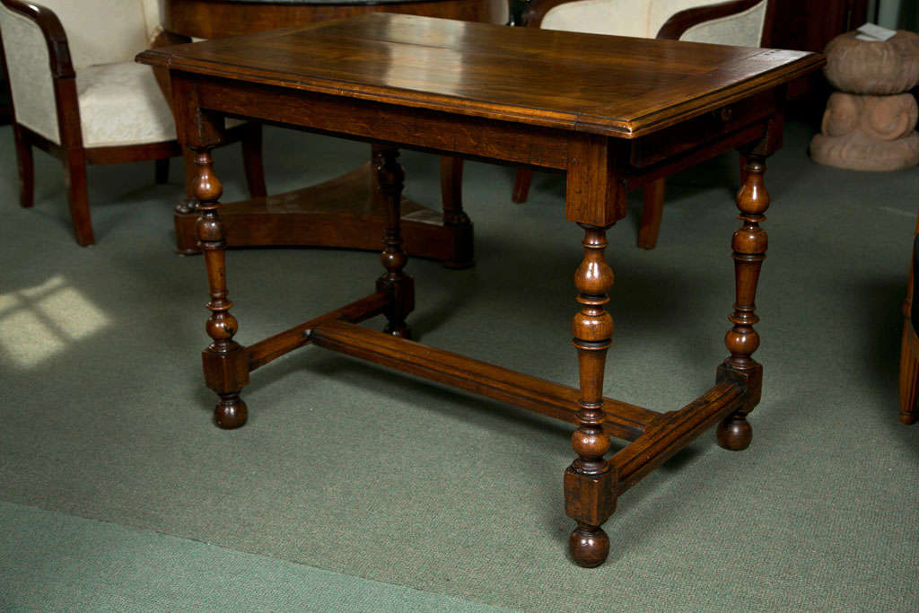 Handsome and generously sized mid-18th century French Louis XIII style table originally intended as a small writing table. Rectangular shaped table shown with one long drawer to one end with hand carved turned legs joined by a stretcher and