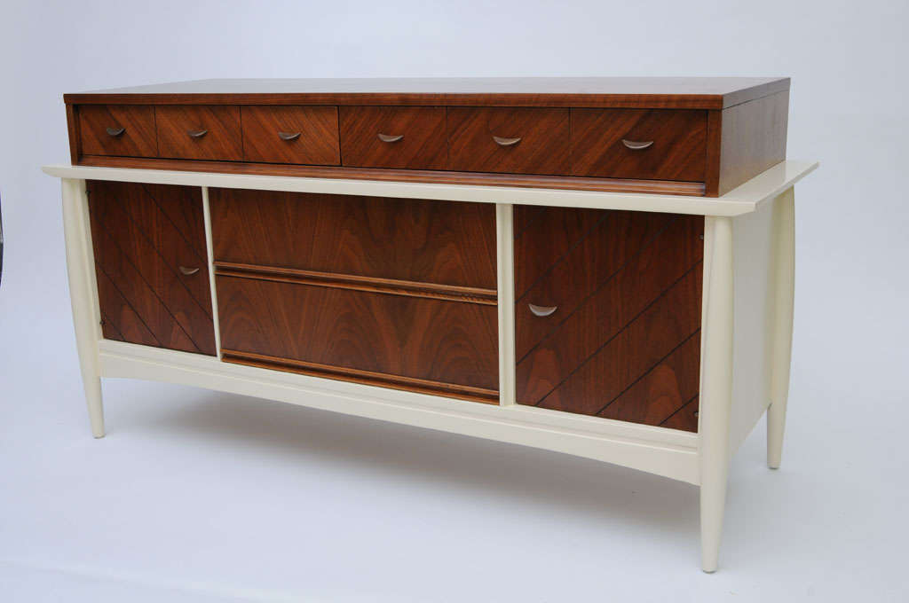 SOLD APRIL 2013 Sleek and exceptional late 50's Modernage credenza buffet featuring richly figured bookmatched walnut veneers throughout.  The top is amazingly beautiful.  The bottom white chocolate lacquered case with tapering lathe turned legs