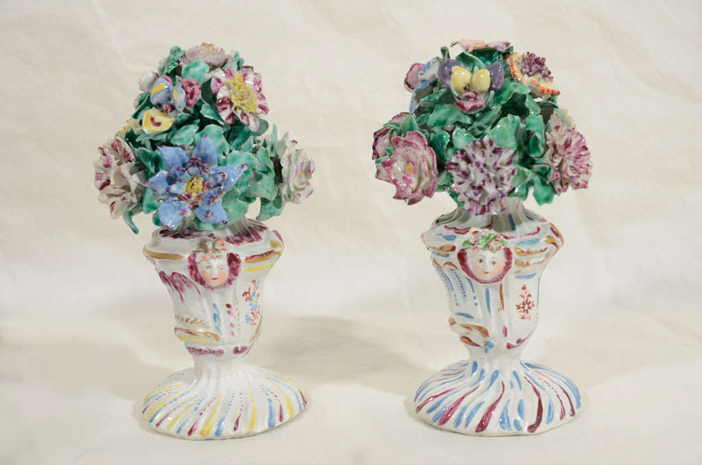 A pair of Bow flower filled rocaille vases with mask handles, made by Bow between 1762-1767.<br />
swirling strokes