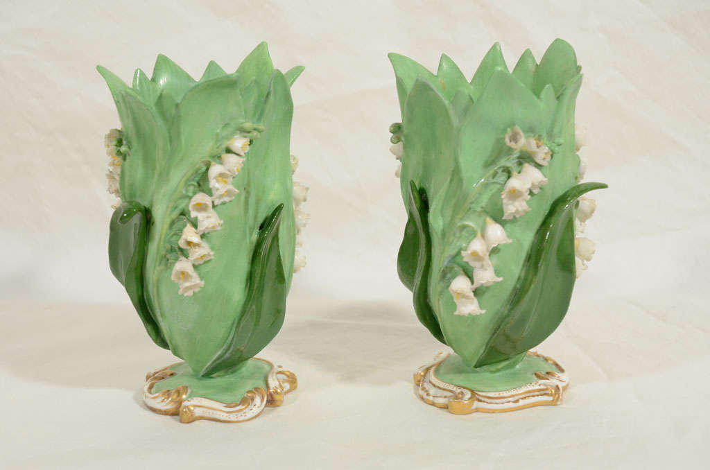 A pair of mid 19th century Minton spill vases in the form of lilly of the valley with typical small white flowers climbing up the green leaves. Naturalistically modeled, on a round base framed with gilt highlighted scrolls.