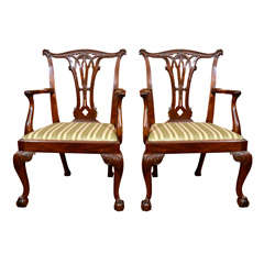 A pair of George III. mahogany carved open arm chairs