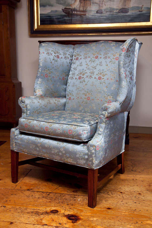 A late 19th century George III style Chinoiserie fabric wing chair. A curved crest above outward scrolling armrests, with deep and curvaceous wings raised on square tapering legs.