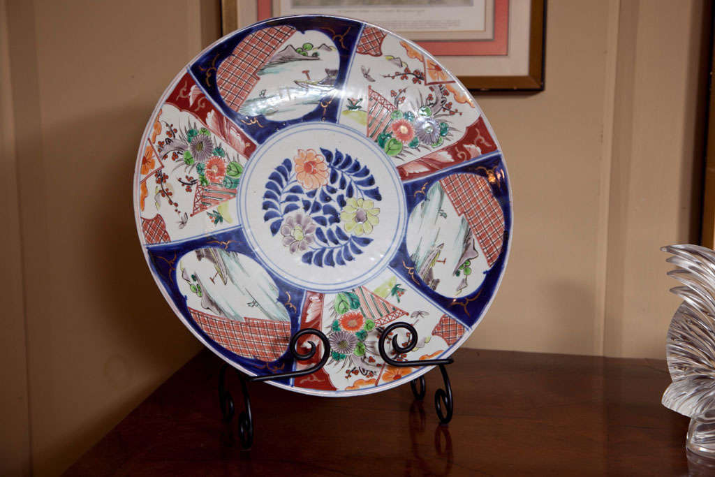 Japanese porcelain Imari Charger, Meiji Period. This charger is of rounded form with six panels containing decorated in polychrome enamels of scenic water views, boats, and floral sprays. The charger features cobalt blue, pale blue, rust red and a