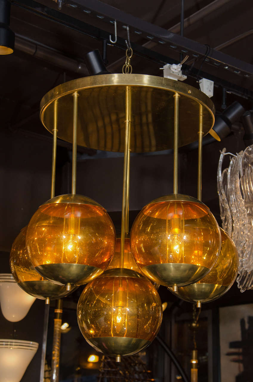 Large circular chandelier with pendant orb design in satin brass.  Features hand blown suspended murano glass globes in hues of amber.  Fitted with six light each. Sold individually at $6,975 each or as a pair for $12,950.
