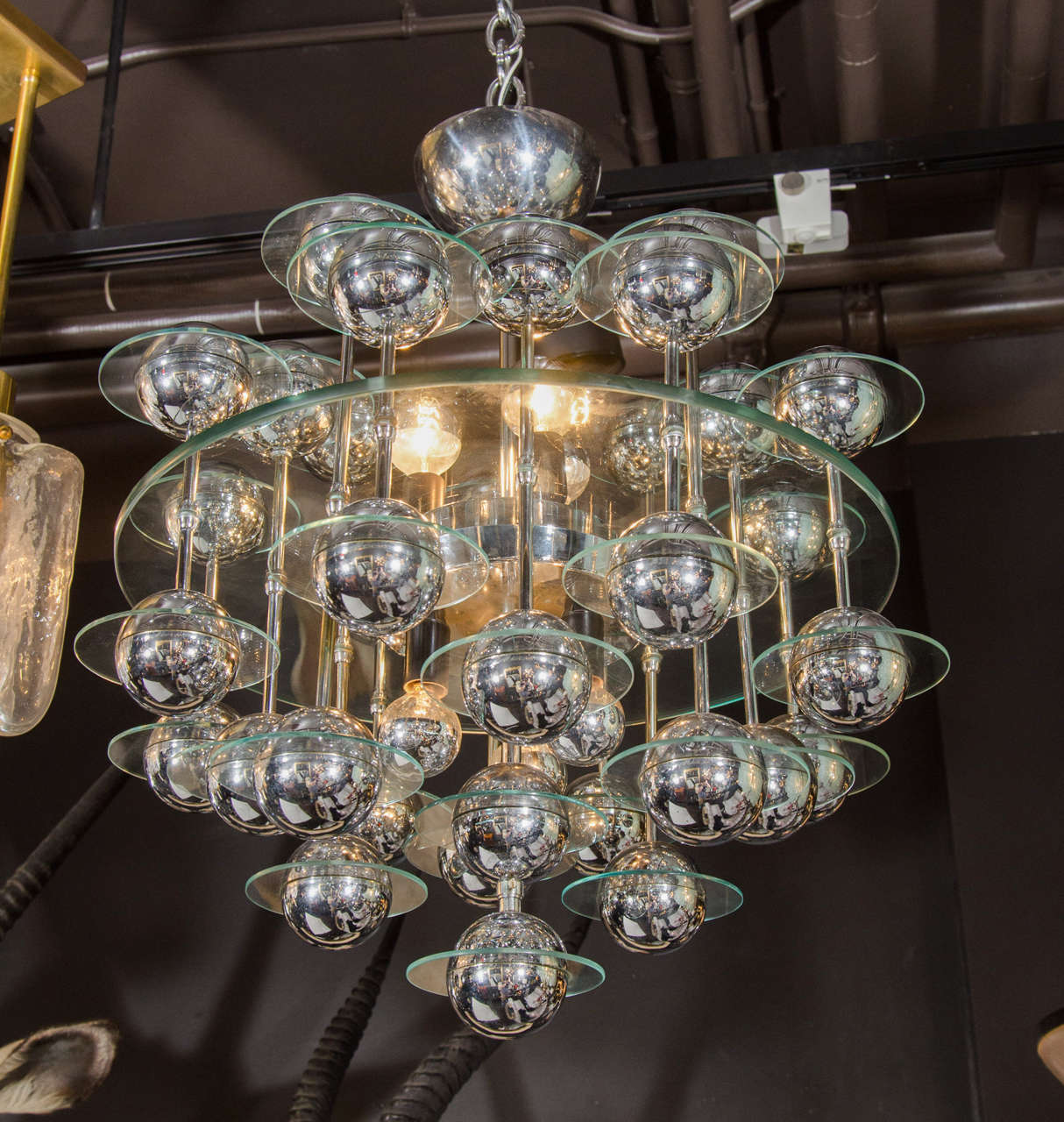 Italian Mid-Century Modern kinetic chandelier with Space Age design. Features central glass disc with suspended spheres of chrome globes. Each orb has a smaller glass disc surrounding it. The spheres hang from chrome rods attached through the center