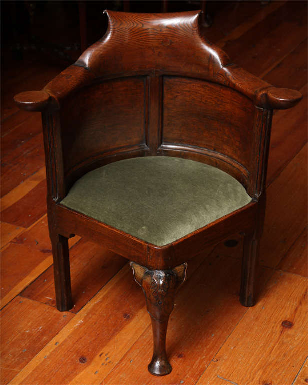 Finely figured George I carved elmwood and oak corner chair with a shaped scrolling crest rail terminating in circular drink rests, above two outcurvate back panels, a shaped slip seat and a front cabriole leg with carved knee ending in a round pad
