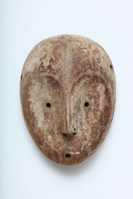 A Finely carved mask from the Yaka people of the Congo. Extremely stylized face with holes for raffia beard.  traces of original crushed shell on the surface of the mask remain.