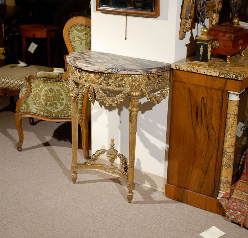A petite louis XVI style gilt-wood console table with marble top, holly leaf detail in frieze with garland drapery below. All supported by fluted and acanthus leaf legs and stretcher with urn. <br />
<br />
For many more fine antiques, please