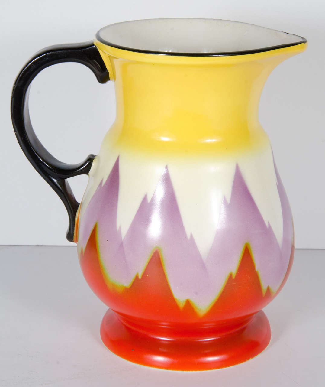 Art Deco pitcher by Ditmar Urbach from Czechoslovakia, Circa 1930.  Hand-painted with hues of red, purple and yellow giving it it's skyscraper flame design.