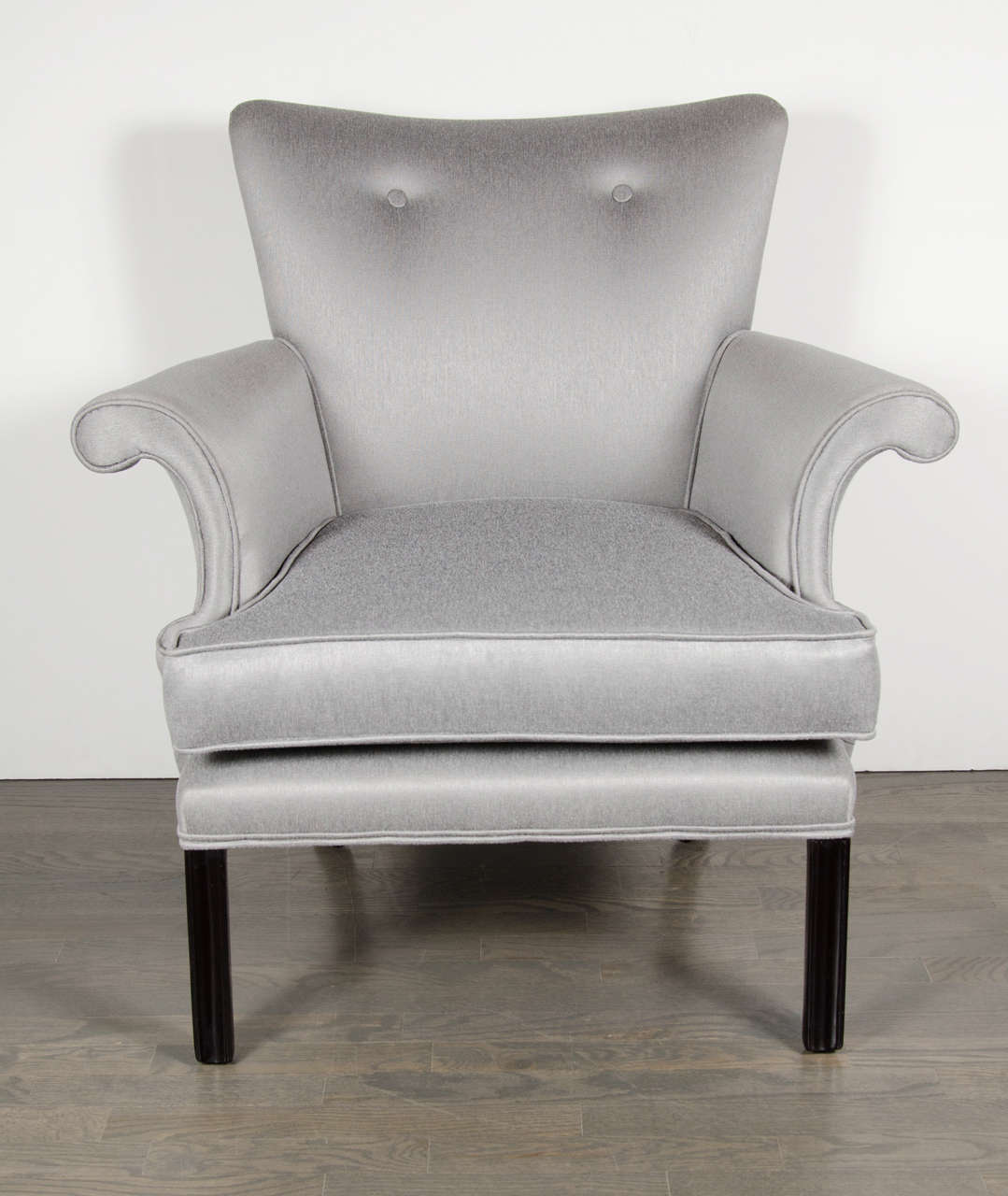 This glamorous pair of Hollywood occasional arm chairs were realized in the United States, circa 1945. They feature button back detailing and stylized scroll arms- newly reupholstered in beautiful platinum sharkskin- as well as rectangular ebonized