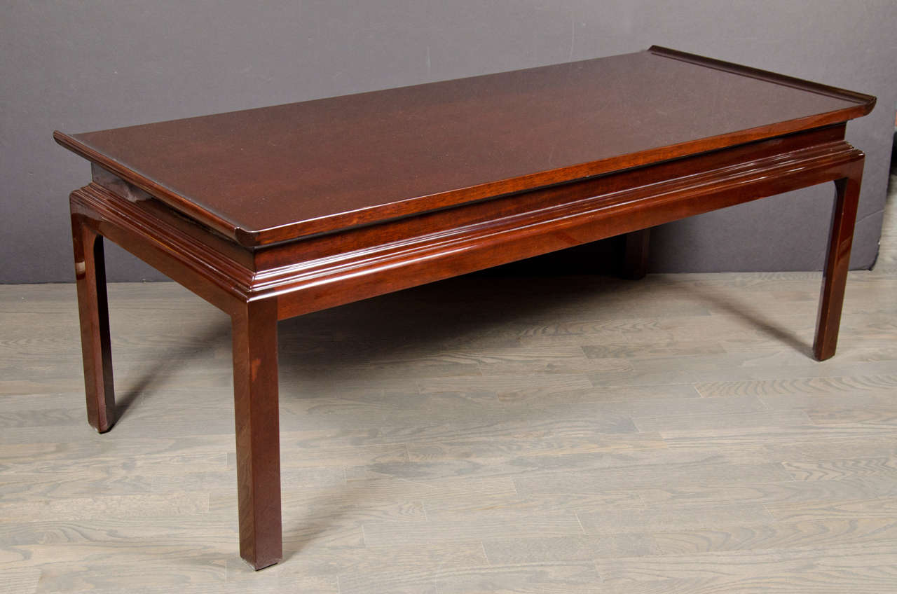 This American Mid-Century Modern cocktail table was realized in the manner of James Mont, circa 1960. It features a pagoda style top resting on a stepped base with column like legs in walnut. With its clean lines and gorgeous finish, this piece is