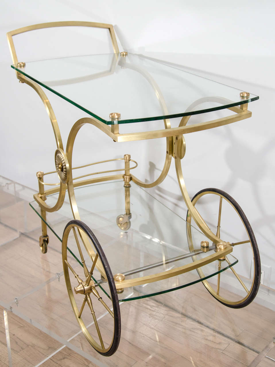 Elegant barcart finished in satin gilt brass with elevated glass tops.