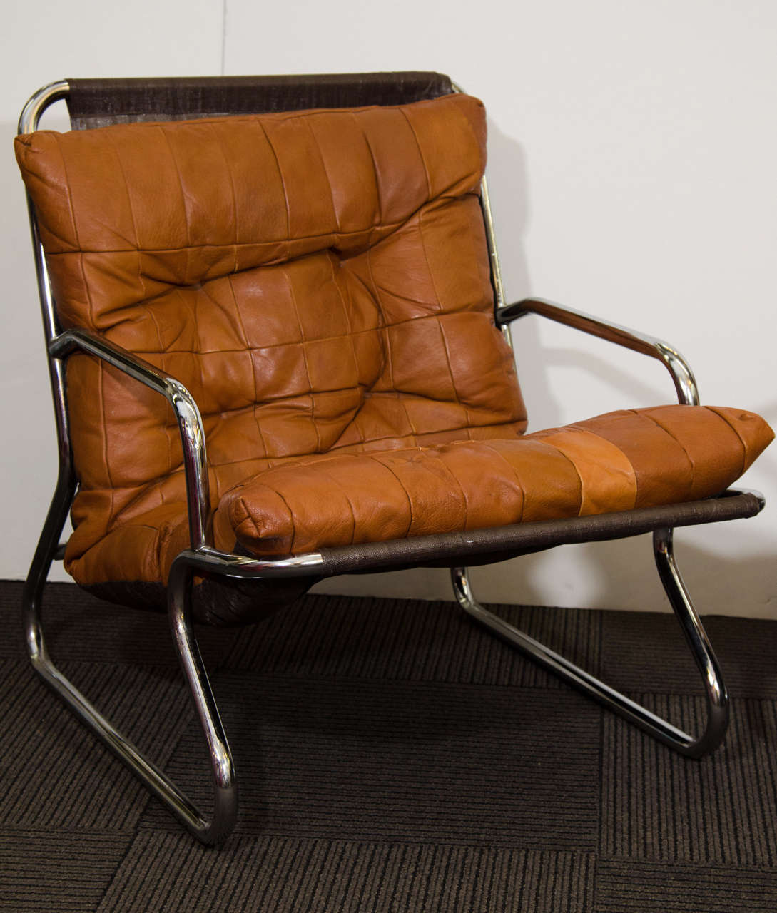 A Danish modern set of two button tufted patchwork leather and tubular chrome lounge chairs. One is a rust colored leather. The other is caramel colored leather.
 