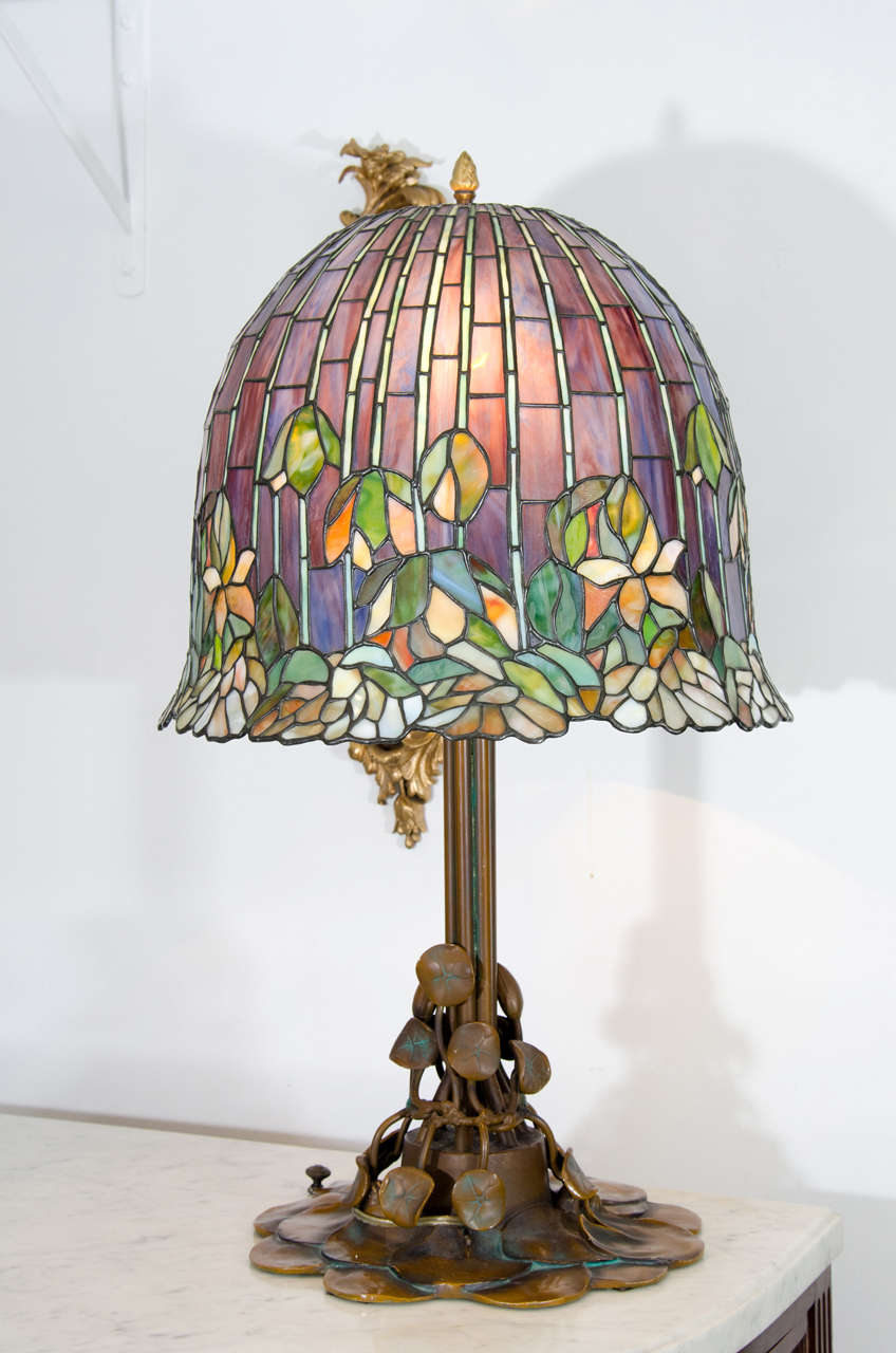 A contemporary stained glass Tiffany style table lamp with lily pad bronze base.

Good condition with a minor crack to shade.