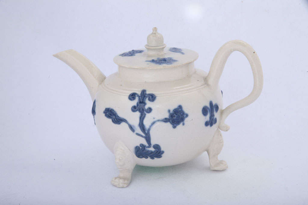 A rare English saltglazed stoneware teapot with applied blue sprigging, acorn finial and three lion's head and paw feet