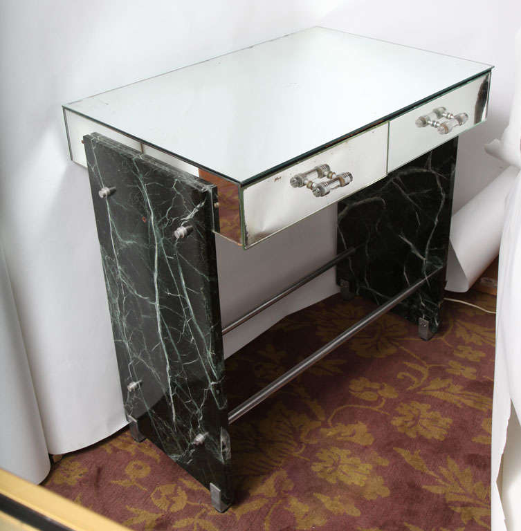 A phenomenal Art Deco vanity/ desk by Adnet combines a two-drawer mirrored top with glass handles, flanked each side by two slabs of solid veined dark green marble and bound together with steel rods sitting on steel feet.