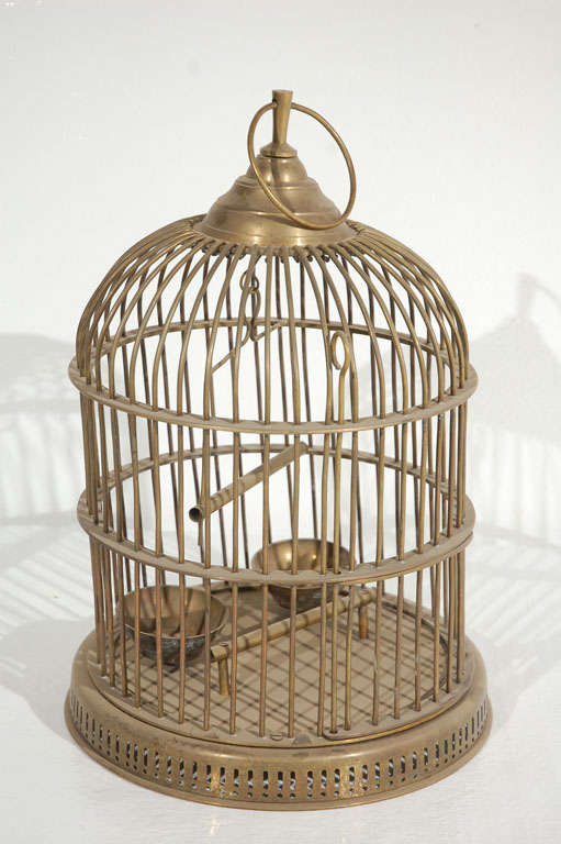 Charming solid brass bird cage with feeding bowls, a swing and a perch. Hangs from a ring at the top and has a large door for access.