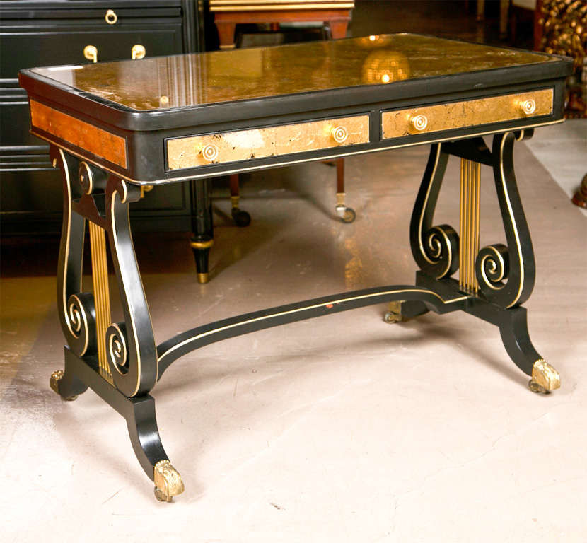 A beautiful French ebonized lady's desk by Jansen, circa 1940s, the top with gilt-glass insert, over a frieze fitted with two narrow drawers, decorated with gilt-glass veneer all around, supported by two lyre shaped pedestals each side,.