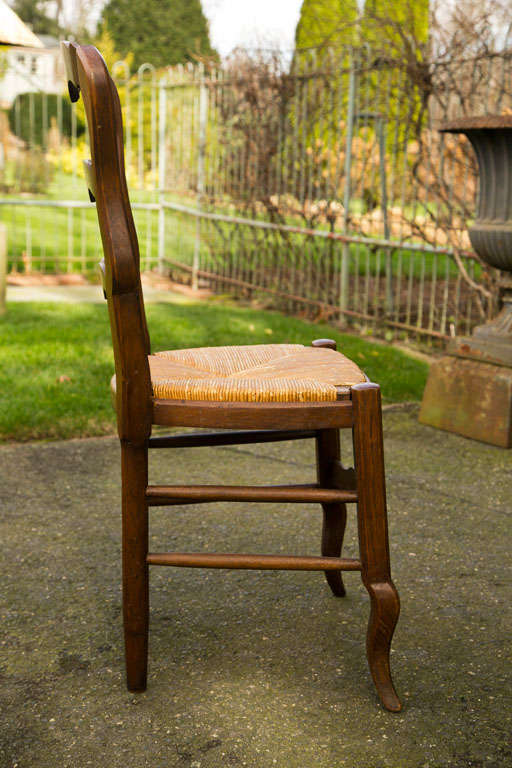 This set of six custom-made carved side chairs has slip seats for easy cleaning or re-rushing. A simple rosette is carved into each crest rail and front stretcher and modified cabriole legs echo the curves of the shaped back rungs. Comfortable for