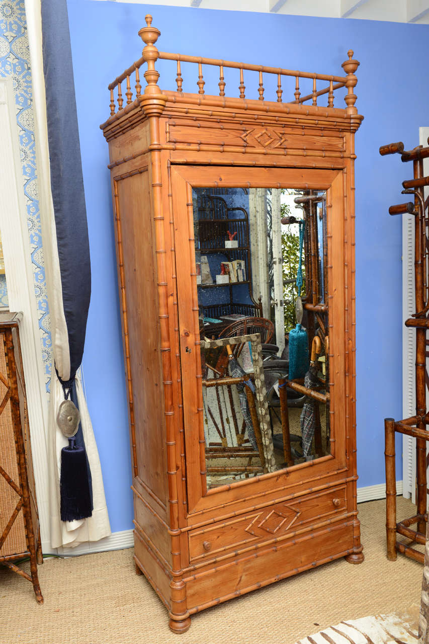 This is a very tall French Faux Bamboo Armoire made from solid pine by the end of the 19th century. While Faux Bamboo Armoires can be found, this particular one is uncommonly tall. It is topped by a cartouche flanked by finials standing upon the