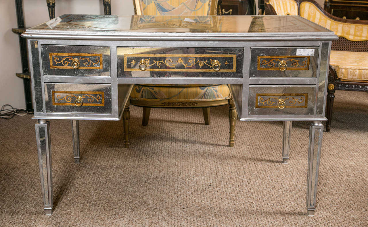 Maison Jansen Verre églomisé French mirrored desk or vanity. The silvered bronze sabots leading to a tapering silver Verre églomisé glass leg supporting a solid walnut desk with all-over leaf, vine and line Verre églomisé decorations. The top