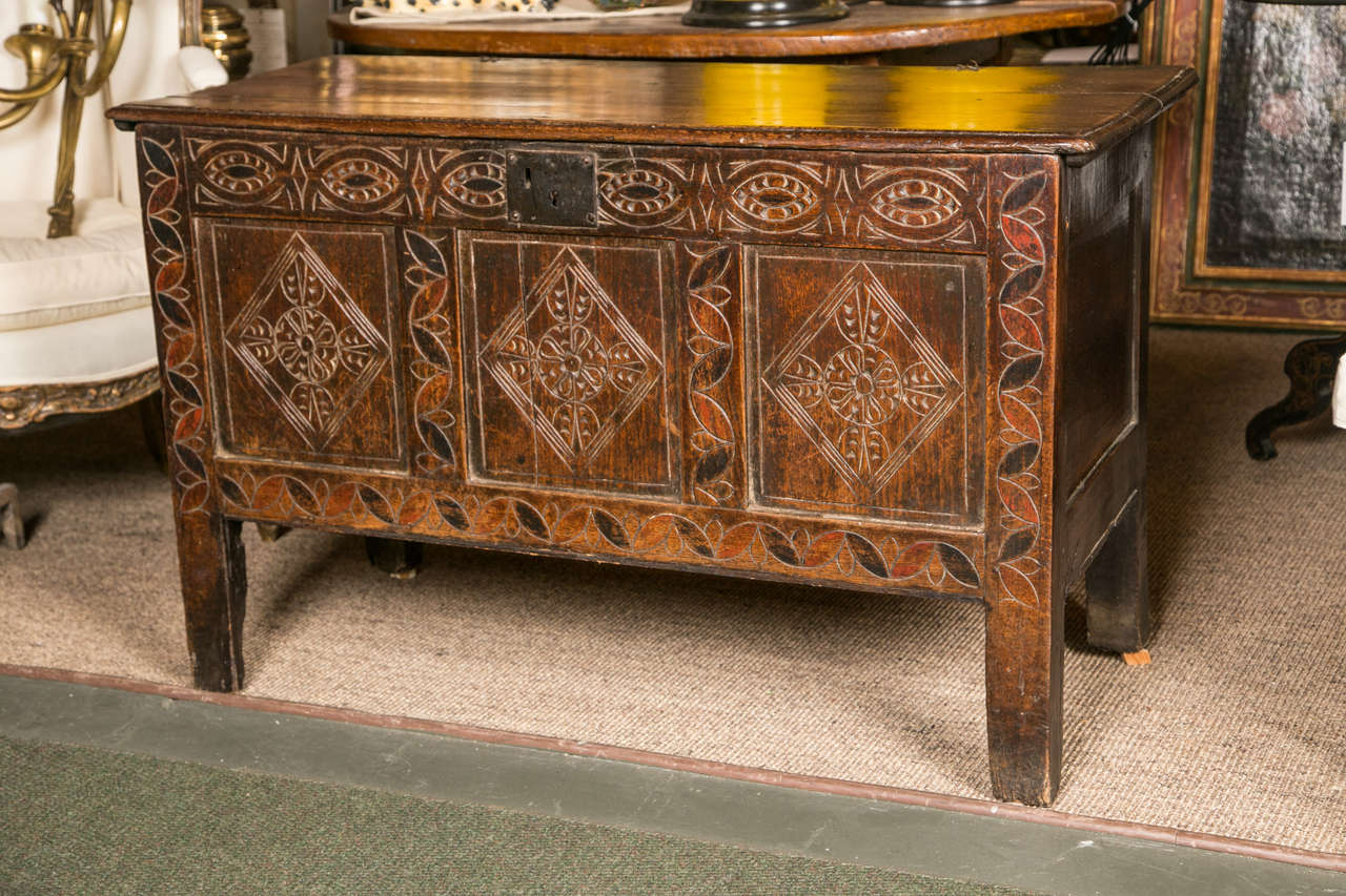 An oak coffer of good color with original black & red painted decoration with scratch carved lozenge to the panels.