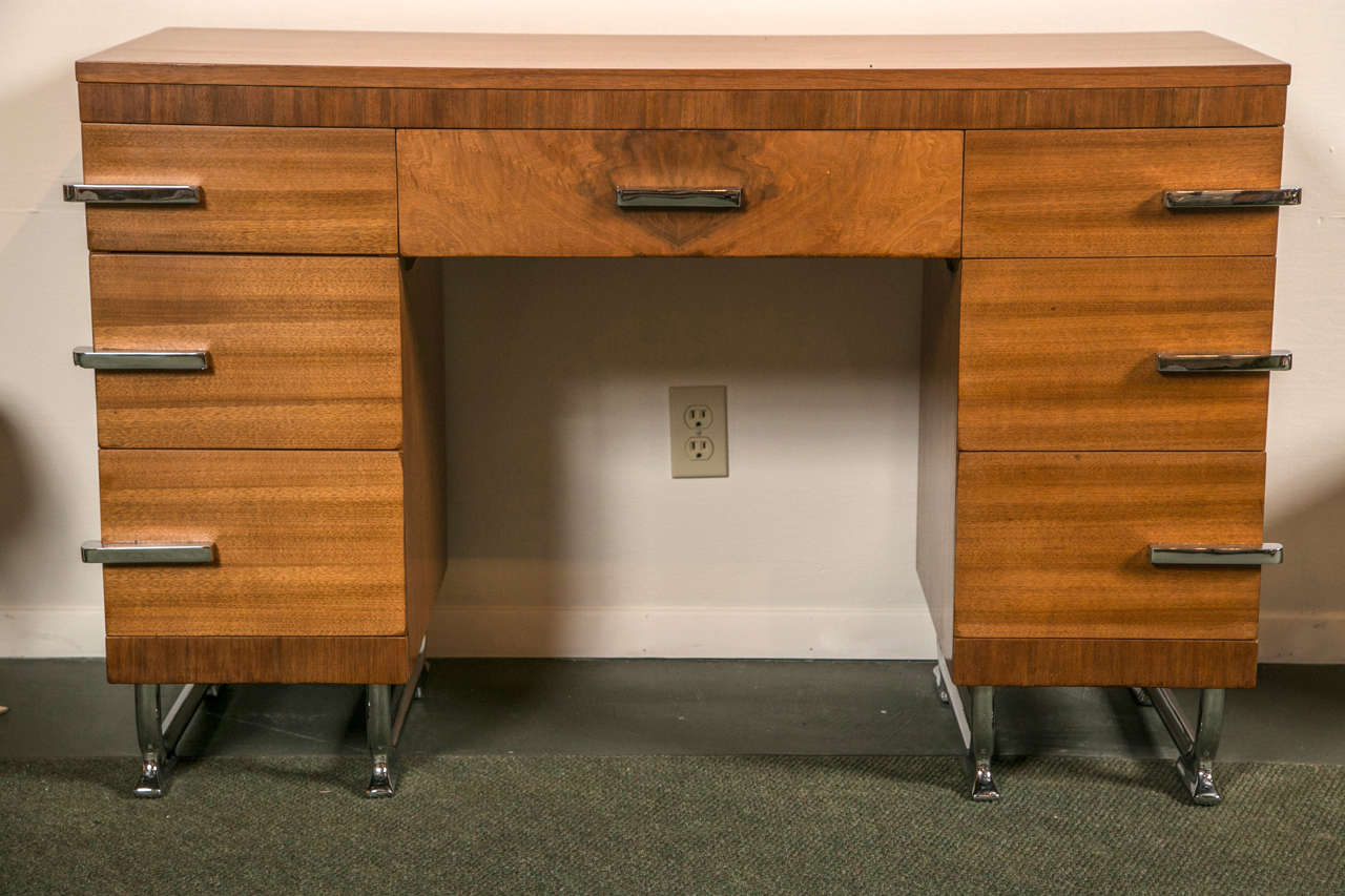 Un meuble-lavabo Art Déco au design épuré, en bois plaqué, avec des poignées et des accents chromés.