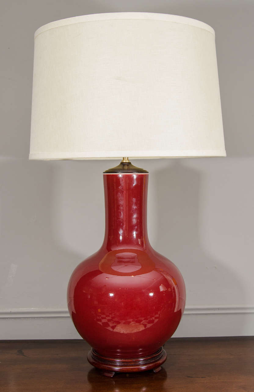 Single Chinese Langyao Hong Oxblood Red Porcelain Vase, Wired as a Lamp. In the tianqiuping or globular form, on a wooden base, with a brass fixture. Shade available separately.

33" H (with harp)
10" Diam. (without shade)