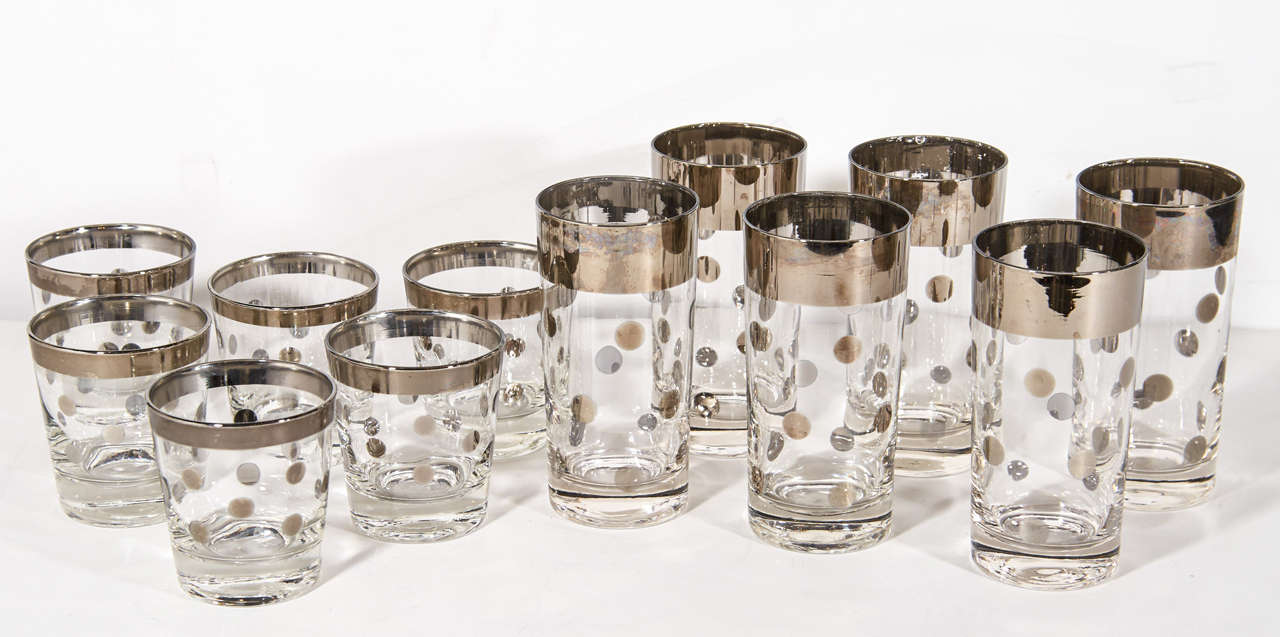 Set of 12 mid century modern cocktail glasses consisting of 6 highball glasses and 6 lowball glasses. The glasses have a mercury silvered metal trim detail with polka dot design.  Adds a  smart and cheerful addition to any bar set.