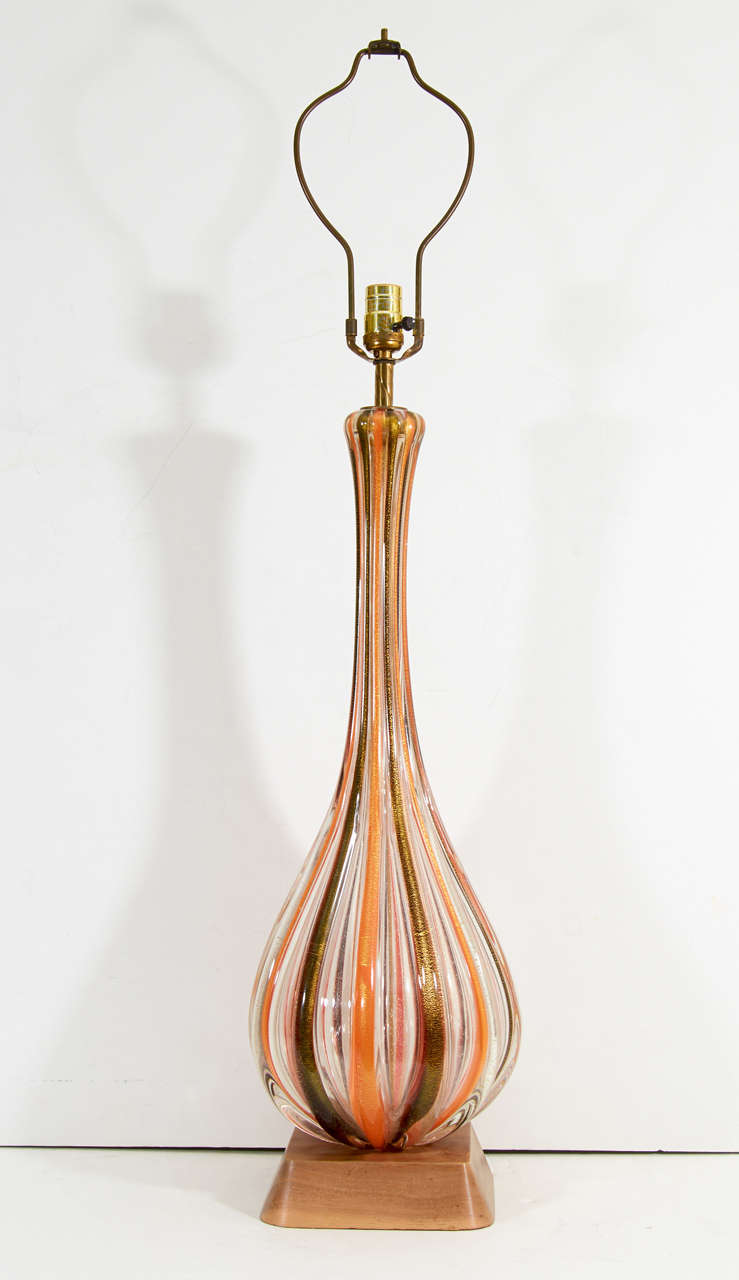 A pair of vintage Murano glass table lamps by Seguso with alternating orange, clear and black stripes with gold flecks throughout.  Each is mounted on a wood base.

Reduced from: $9,500