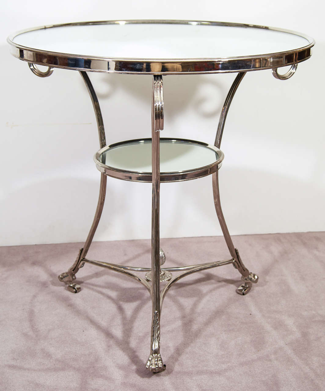 A vintage pair of two-tier glass and chrome side tables with curved legs and paw feet in the style of Maison Jansen. Each has a lower circular glass shelf.