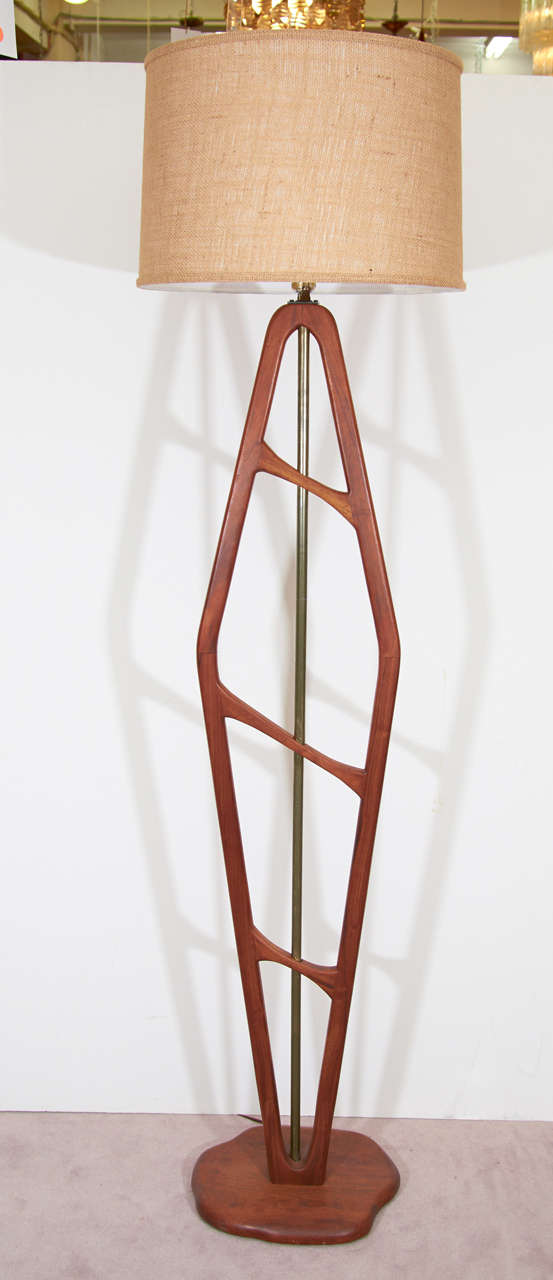 A vintage floor lamp with a stylized Danish Modern teak wood body around an exposed brass rod.