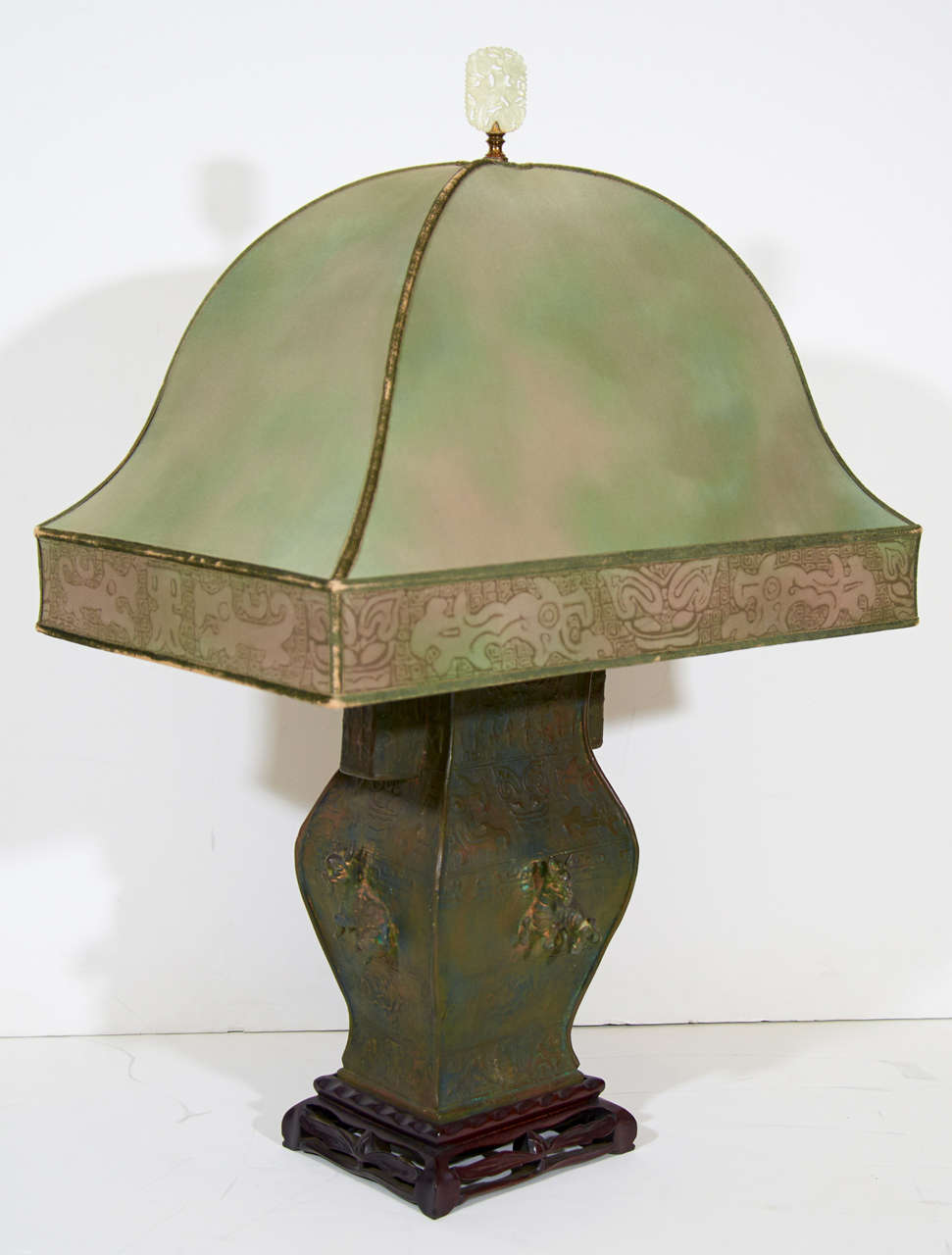 A pair of c. 1920's Chinese patinated bronze table lamps on carved rosewood bases with jade finials and later addition Asian inspired American shades (c. 1940's). They have age appropriate patina and wear to shades and bodies.