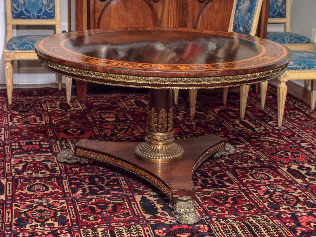 English Regency rosewood supper table with intricate yew marquetry inlay and extensive bronze mounts. The apron is mounted with foliate design bronze. The central pedestal has acanthus climbing up from a fluted collar and the trifed base has inset