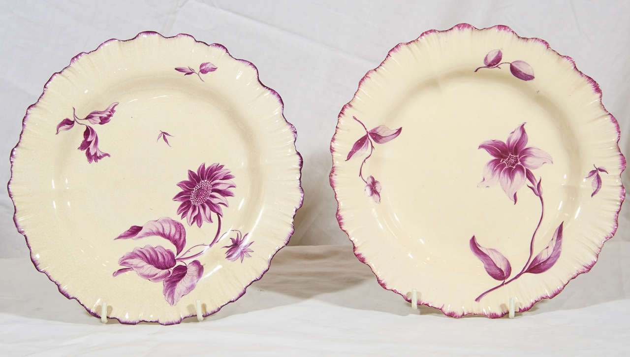 A pair of 18th century creamware ('Queen's ware') dessert plates painted in purple enamel with flowers, made in Staffordshire, England at Josiah Wedgwood's factory circa 1770 with fluted shell edge borders and irregular rims. Probably painted by