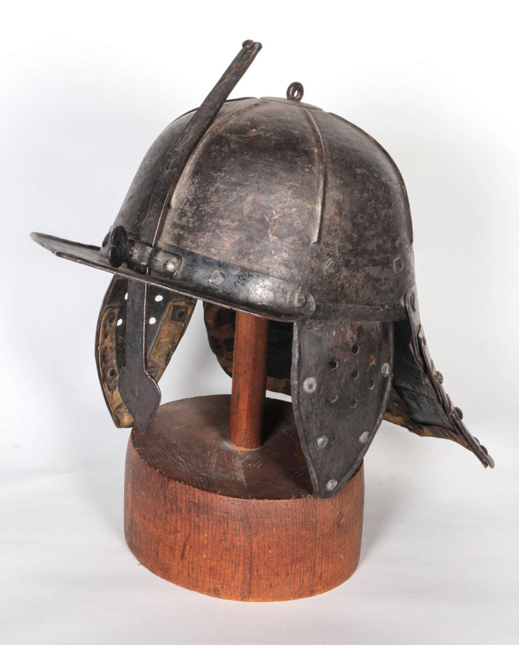 English, circa 1640's Roundhead (Parliamentary) helmet. Made of mill-rolled steel and riveted construction. It has a 'lobster tail' articulated neck guard and adjustable nasal guard secured with a heart-shaped wing nut. The helmet's textured surface