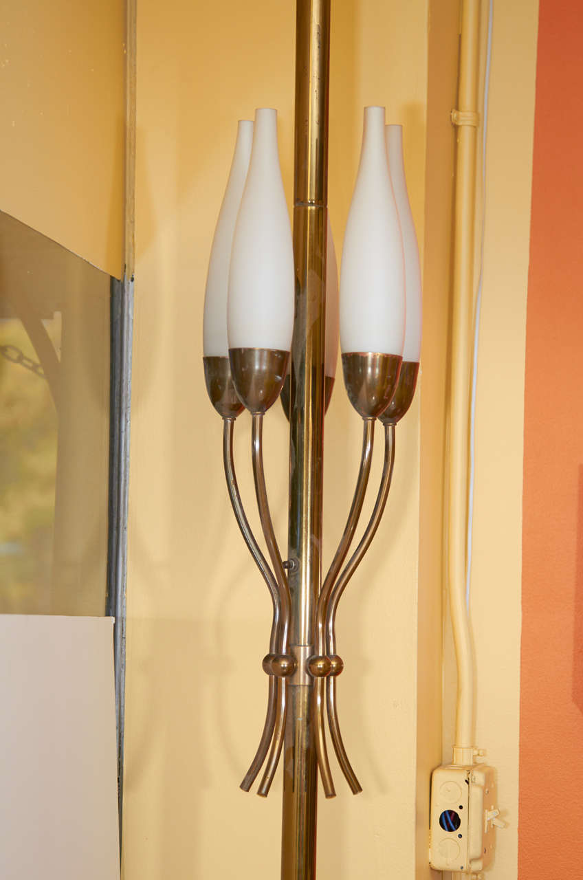 Beautiful lamp in the style of  Angelo Lelii for Arredoluce. This brass floor lamp has a gracefully designed cluster of Lelii's signature frosted candle shades. It is a pole lamp with spring loaded mounts to fix the lamp in place between floor and
