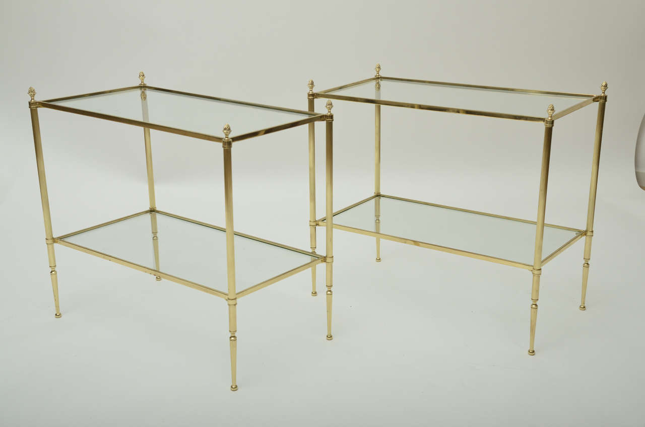A pair of 1940s Bagues-style two-tier brass side tables with acorn finials, reeded leg and fluted foot.