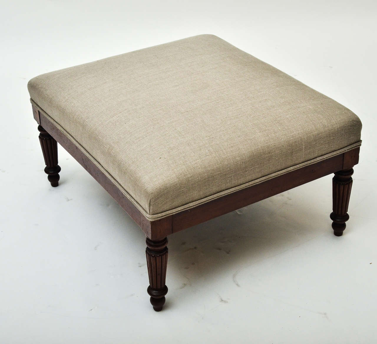 An early 19th century upholstered stool with turned and fluted mahogany legs, and upholstered in linen.