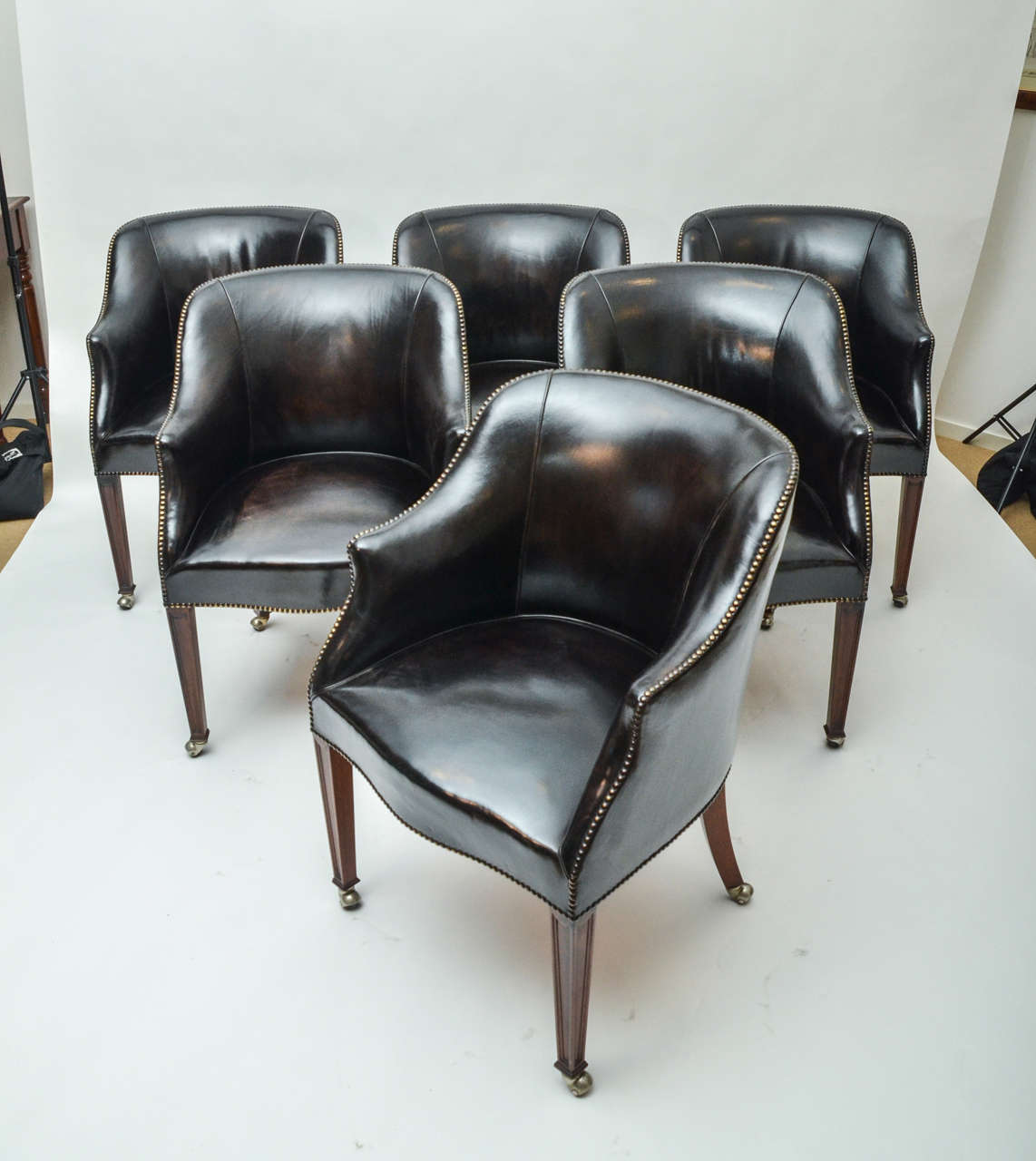 A set of six leather upholstered chairs from the Carlton Club in London, brass studs, mahogany legs, and original casters. Pair available: $3,500