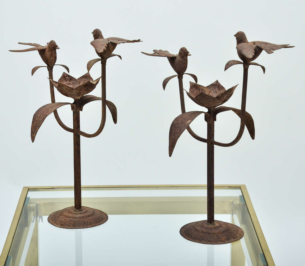 A pair of Anglo-Indian iron candleholders, attractively worn, rusted iron, each designed with a pair of iron birds.