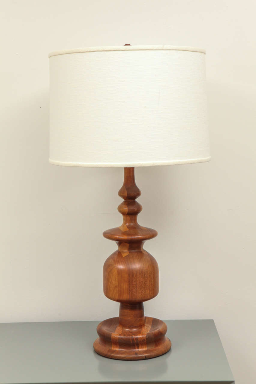 This mid century table lamp is well-scaled and masterfully turned from a solid piece of vividly grained teak, adding visual interest to any room.