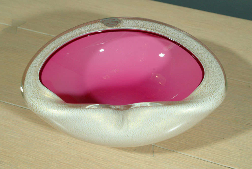 A large, freeform, cased glass bowl by Alfredo Barbini, circa 1960 with interior in bubblegum pink and exterior in gold aventurine-flecked white. Retains original foil label.