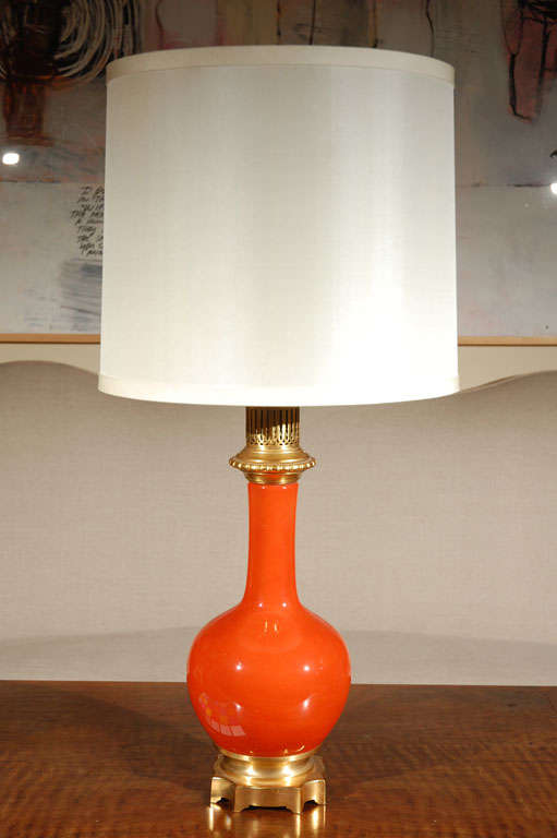 Turn of the century, glazed, orange lamp with gilded bronze foot and neck.