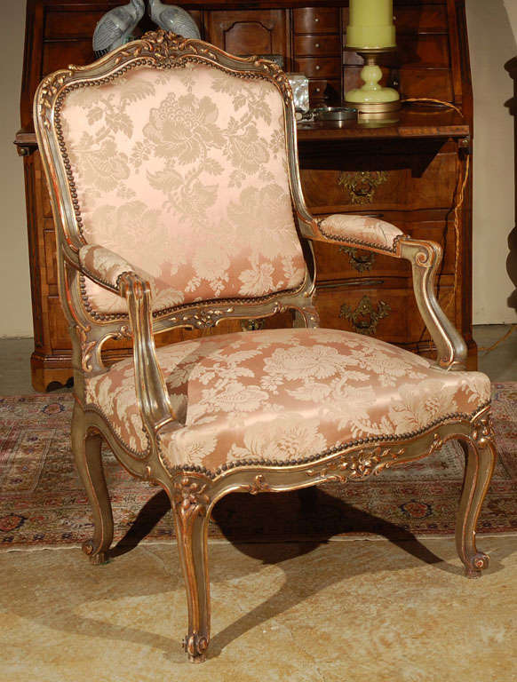 Hand-carved French Regence style armchair with gilding and brass nail heads.